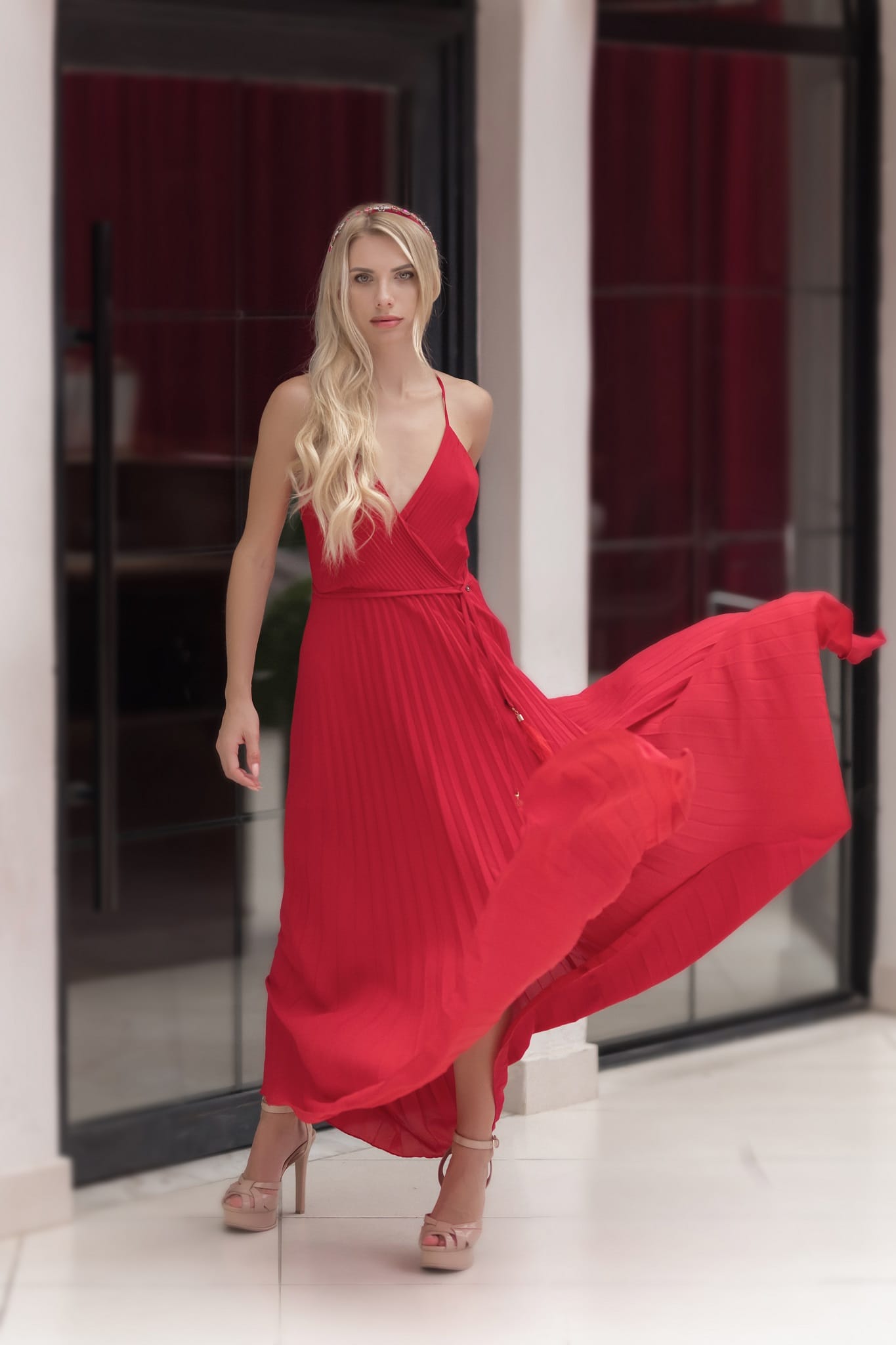 model  in a red dress standing in front of a mirror.