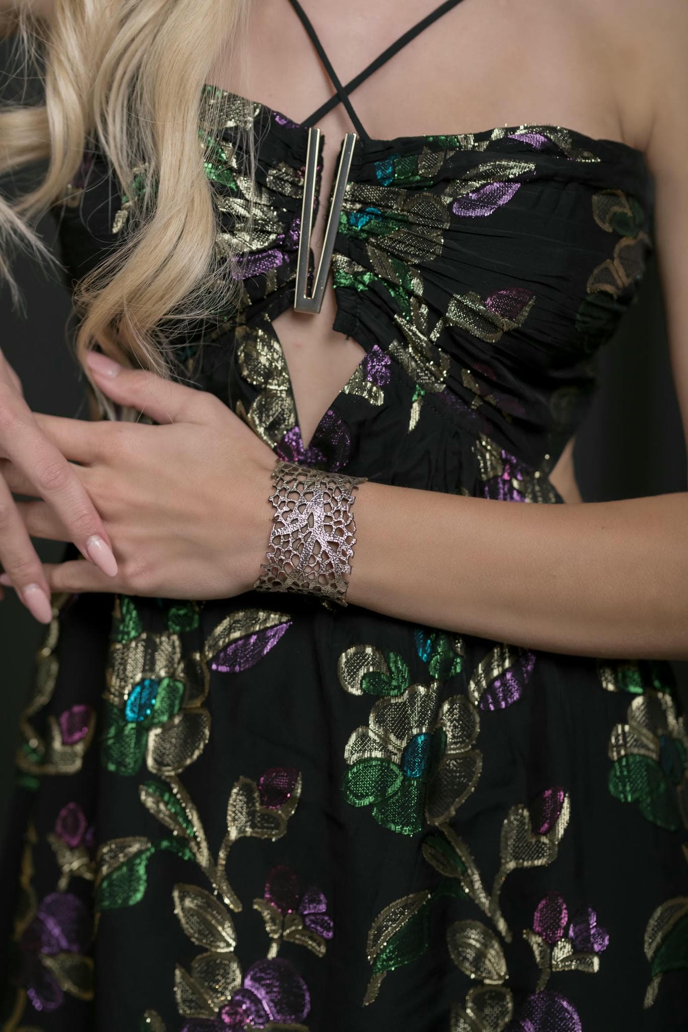Black dress with gold floral embroidery and a silver bracelet on a dark background