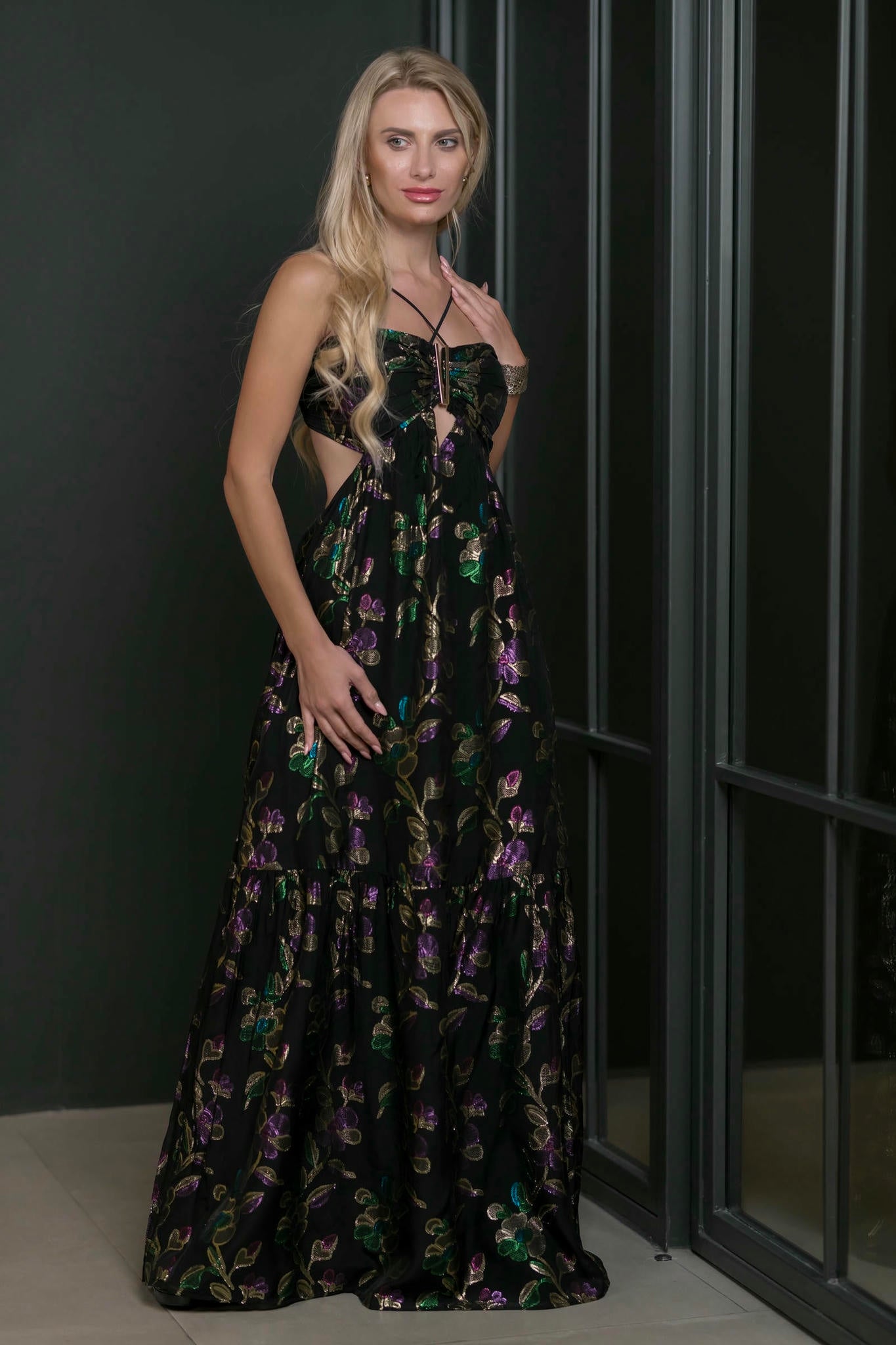 Woman wearing a black floral evening gown against a dark background