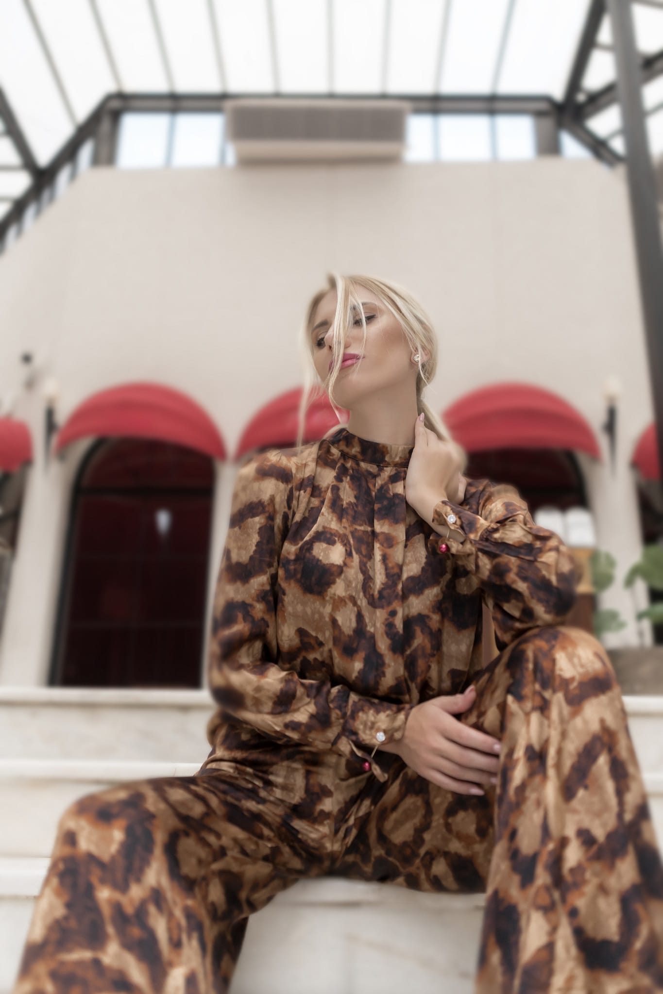 model wearing a leopard print outfit sitting on steps with a blurred background