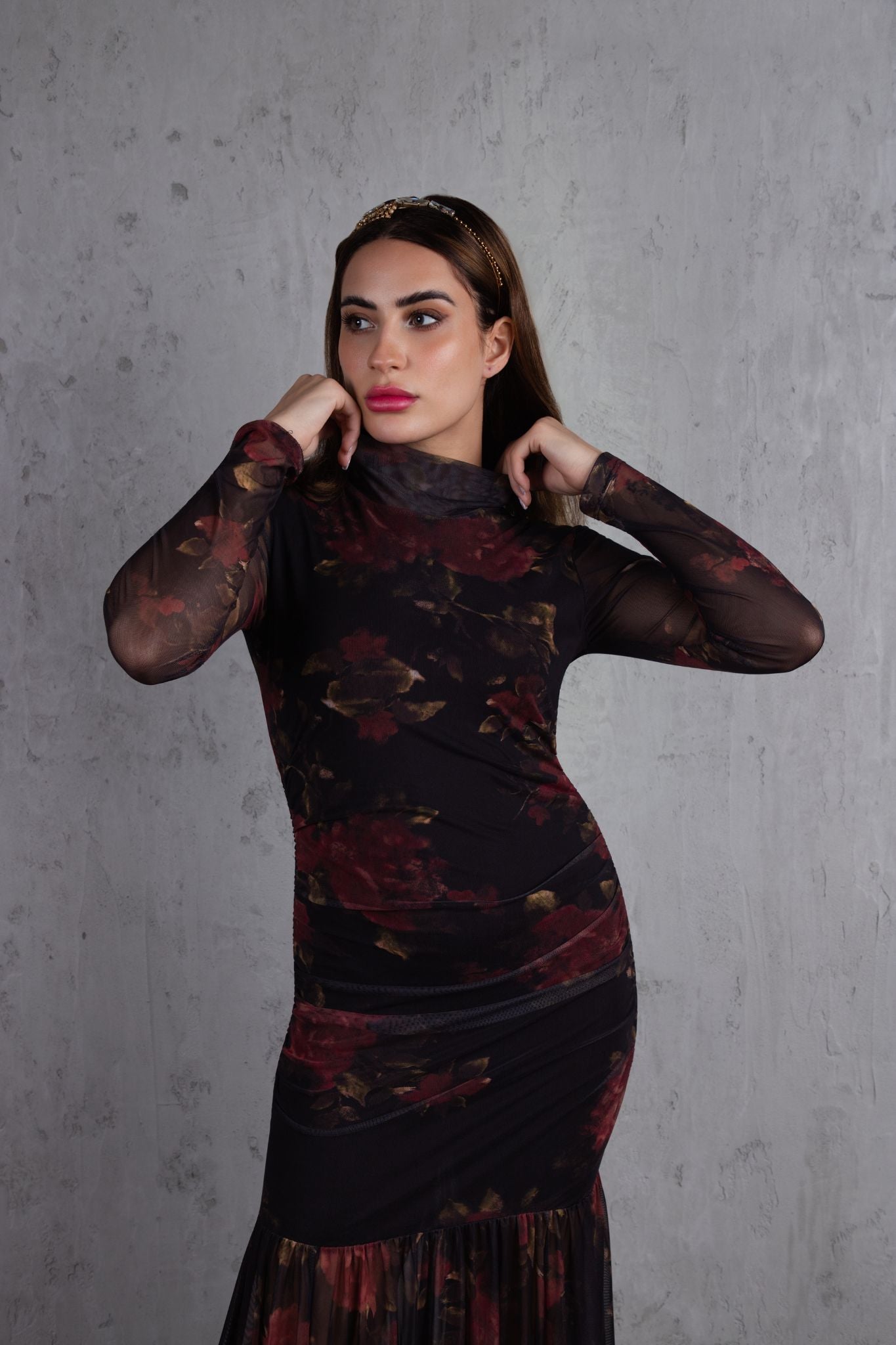 Woman wearing a dark patterned dress against a gray background