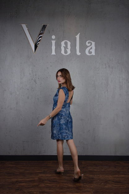 Woman in a blue dress standing against a gray wall with 'Viola' branding.