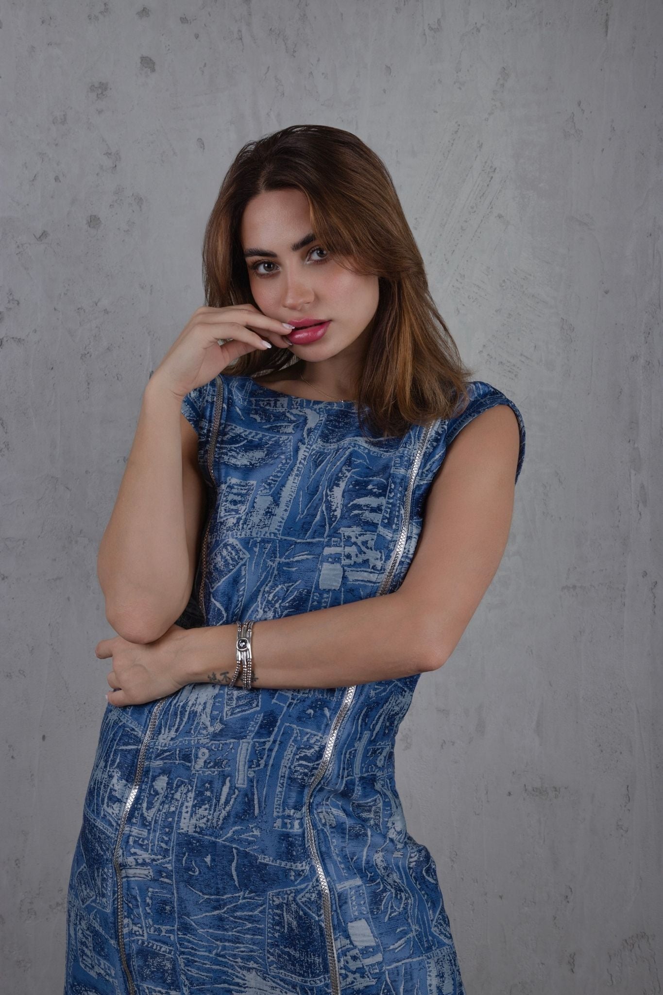 Woman wearing a blue patterned dress against a gray background
