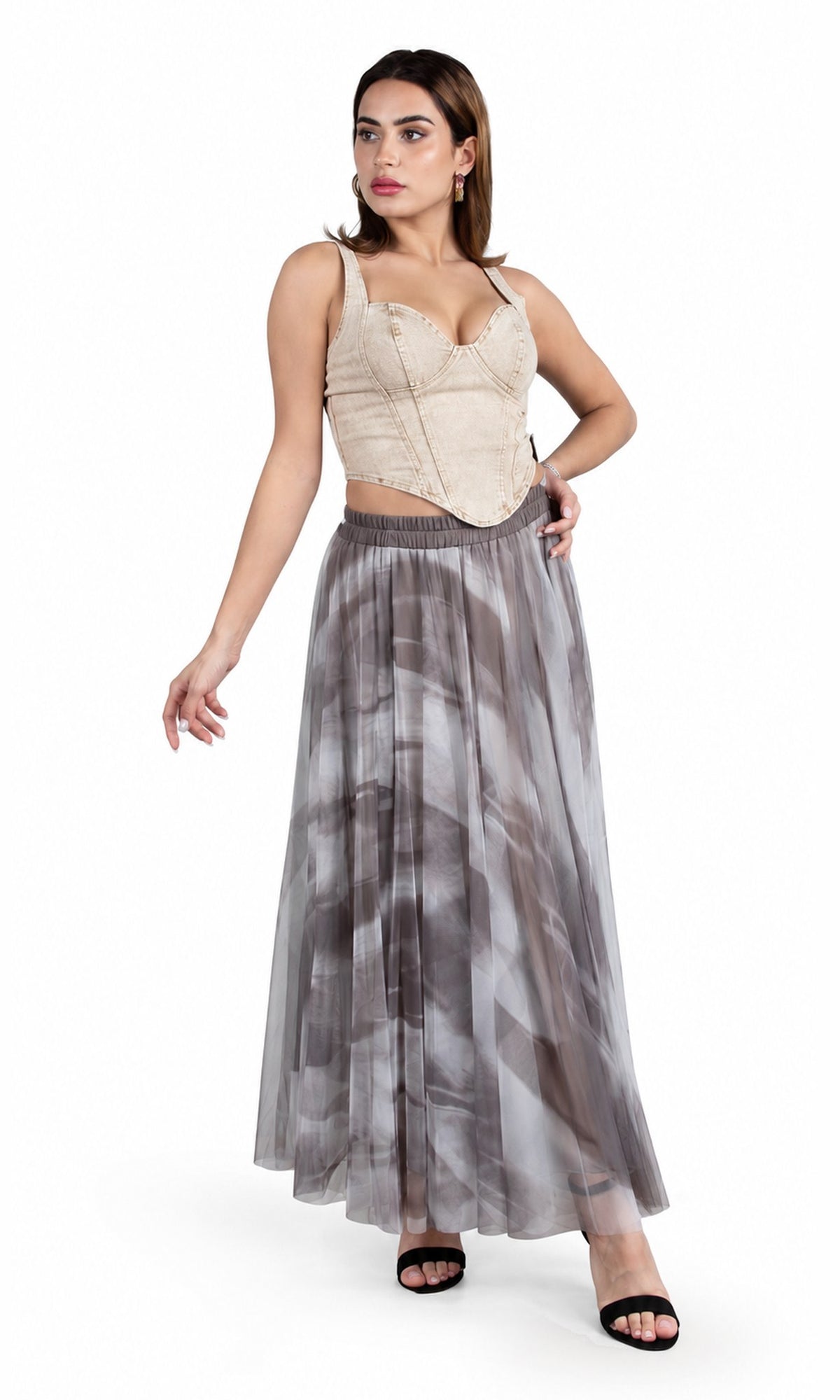 A woman modeling a two-piece outfit consisting of a beige lace-trimmed crop top and a long gray and white abstract-print tulle skirt, paired with black slide sandals, against a plain white background.