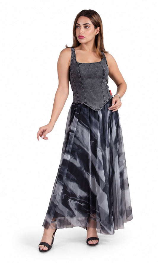 A woman modeling a sleeveless maxi dress with a structured charcoal gray corset-style bodice and a flowing sheer skirt in a black, gray, and white abstract pattern, set against a plain white background.
