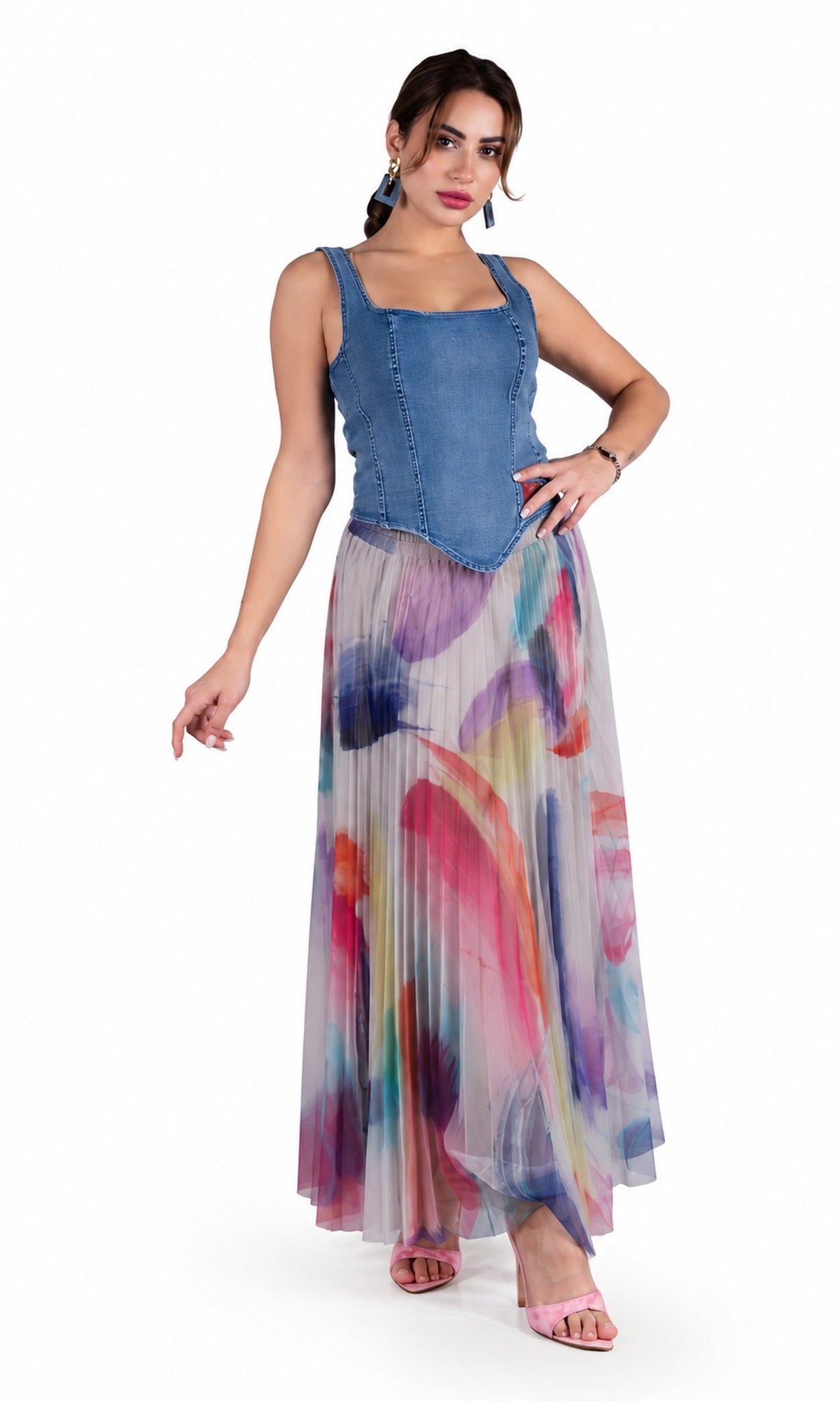 A woman modeling a sleeveless maxi dress with a blue denim corset-style bodice and a flowing pleated skirt featuring a colorful abstract watercolor print in pink, purple, blue, yellow, and orange, set against a plain white background.