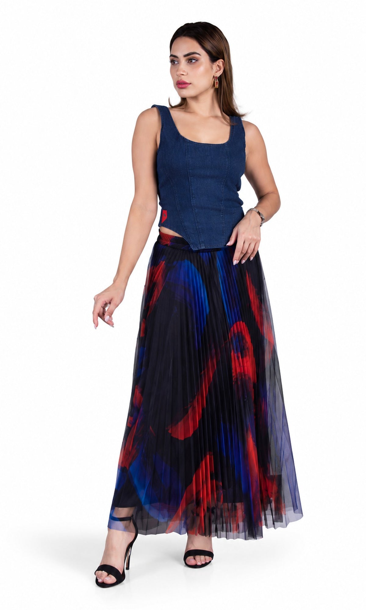 A woman modeling a sleeveless navy blue top and a long pleated tulle skirt with a red, blue, and black abstract print, set against a plain white background.