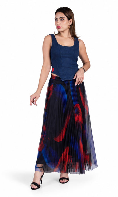 A woman modeling a sleeveless navy blue top and a long pleated tulle skirt with a red, blue, and black abstract print, set against a plain white background.