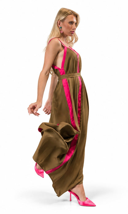 A woman modeling a sleeveless brown maxi dress with bright pink satin-like trim and matching pink high heels against a plain white studio background.