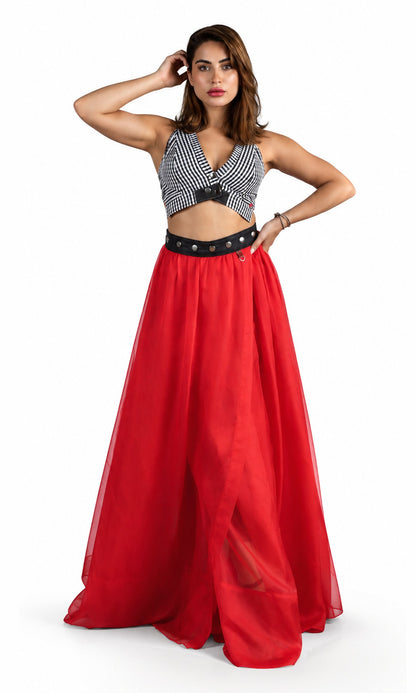 A woman modeling a two-piece outfit featuring a black and white striped halter crop top and a flowing red maxi skirt with a black studded waistband, set against a plain white background.