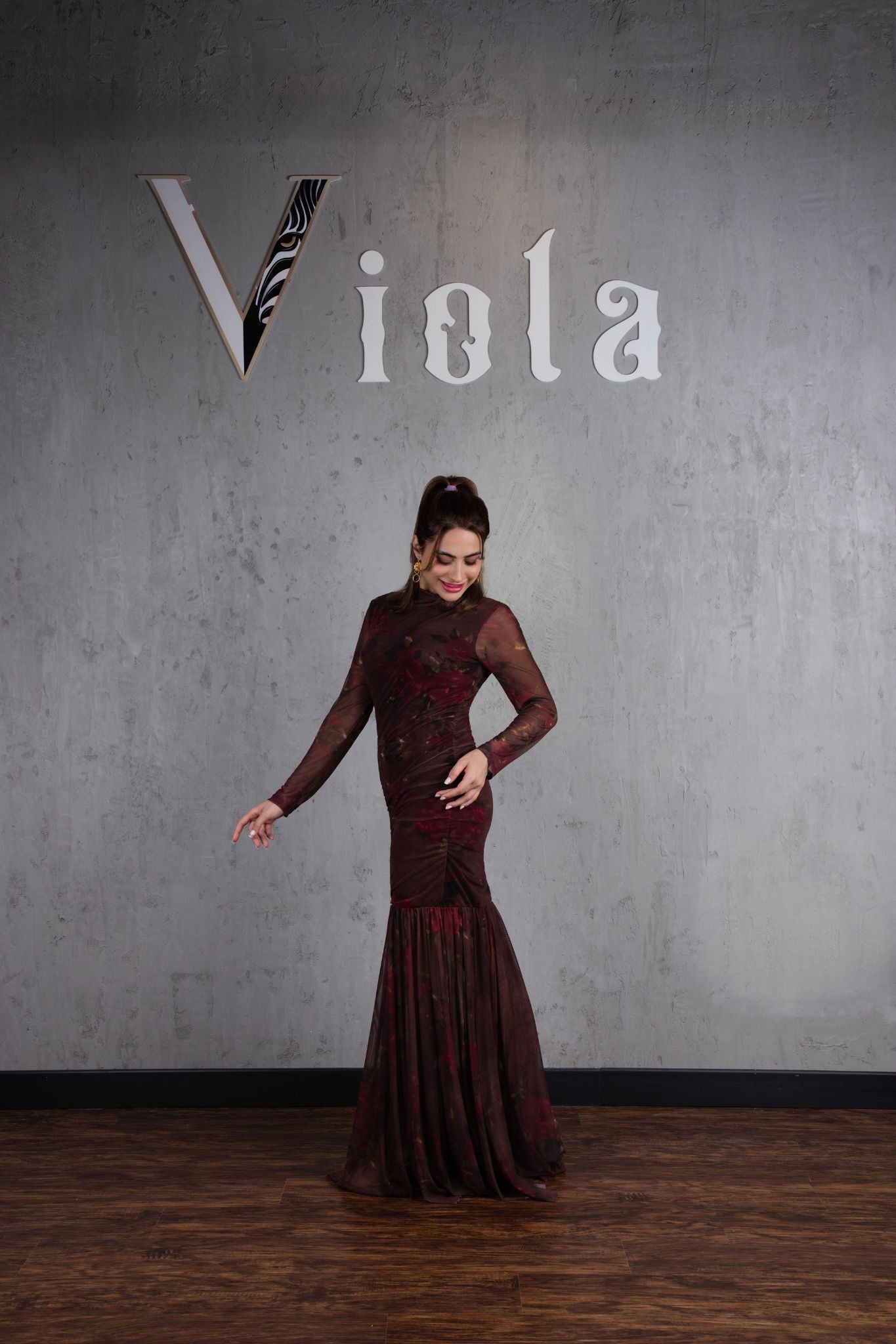 Woman in a red dress standing against a gray wall with 'Viola' branding.