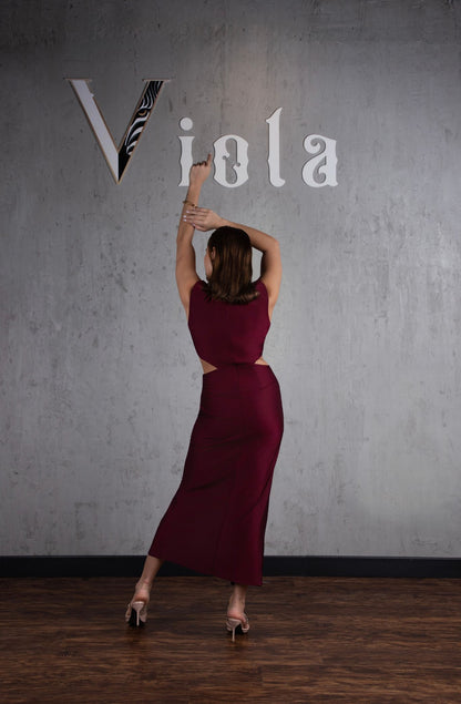 Woman in a burgundy dress holding a zebra-striped flag against a gray wall with 'Viola' written on it.