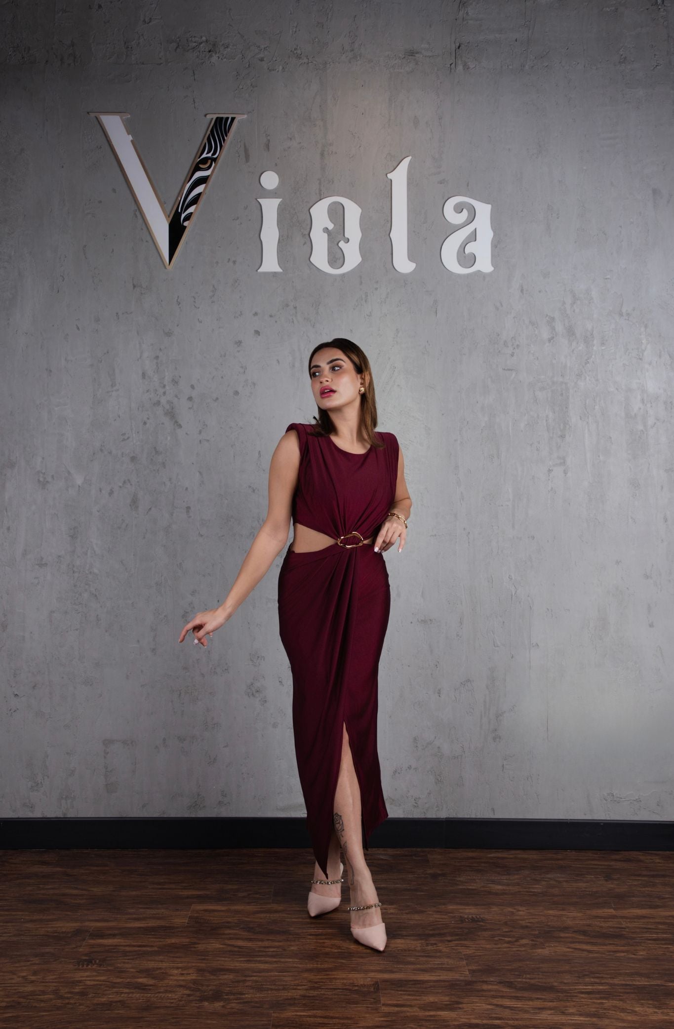 Woman in a burgundy dress standing against a gray wall with 'Viola' branding.