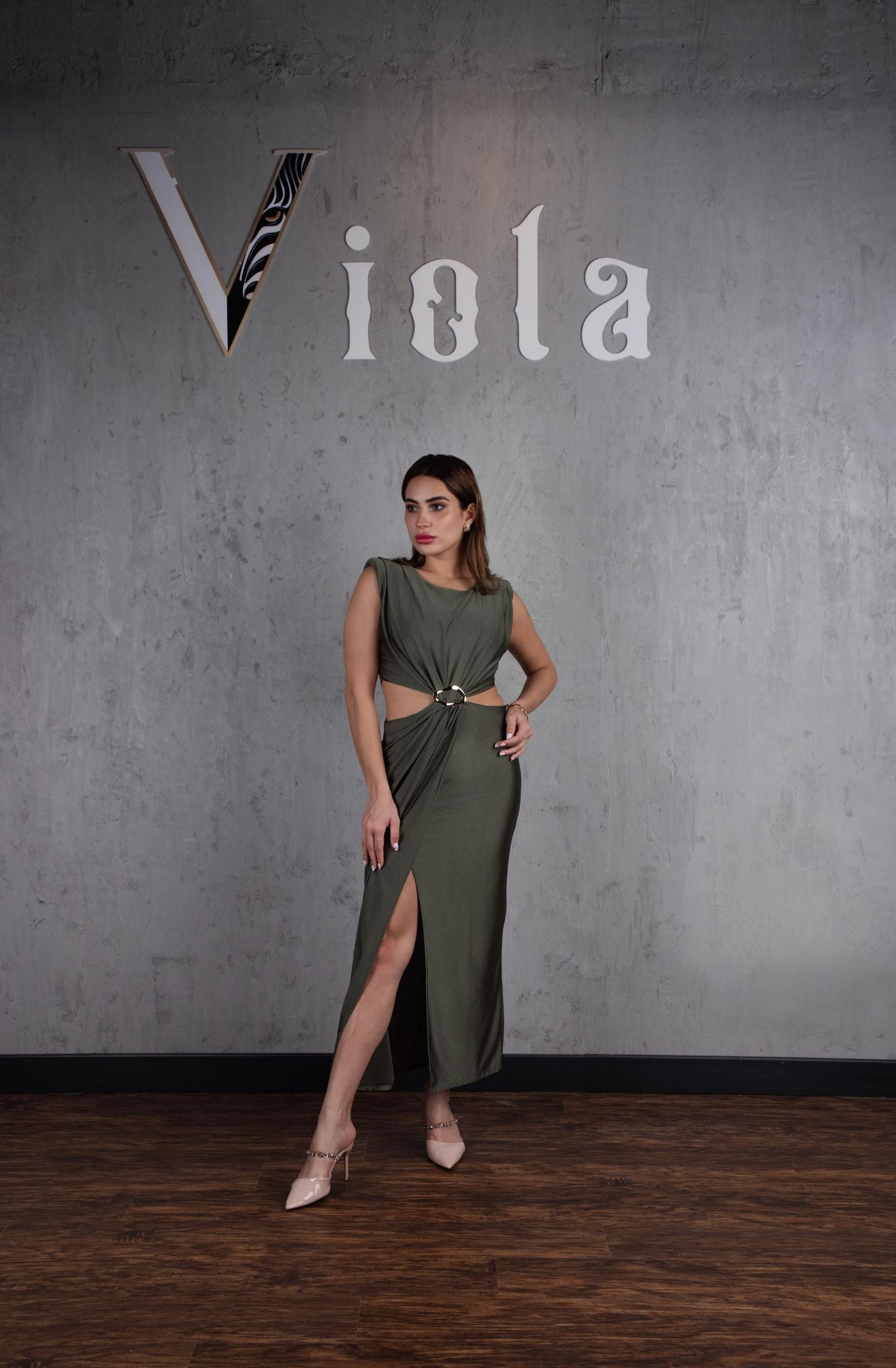 Woman in a green dress standing against a gray wall with 'Viola' branding.