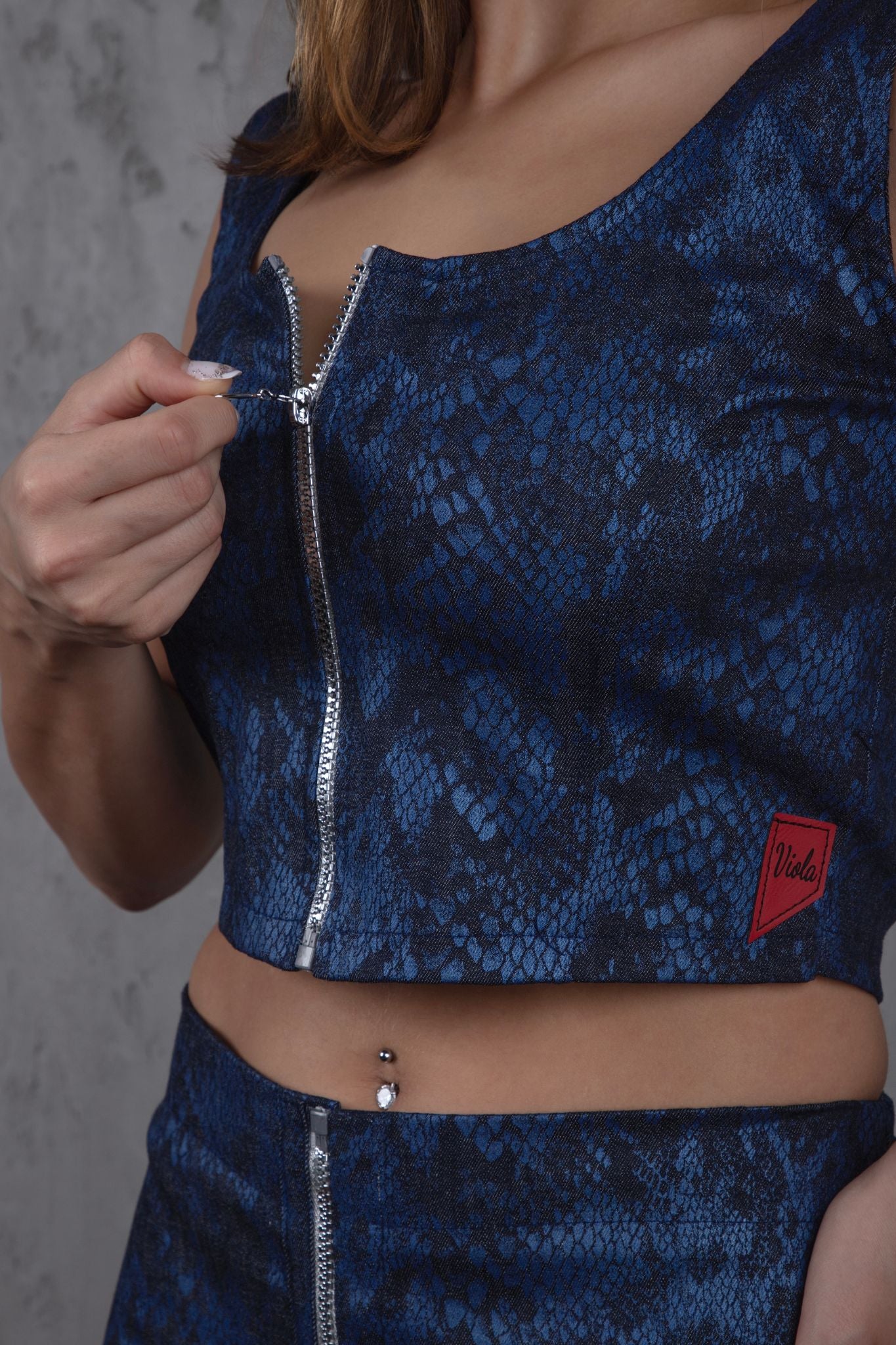 Blue patterned top with a zipper and brand logo on a blue denim background