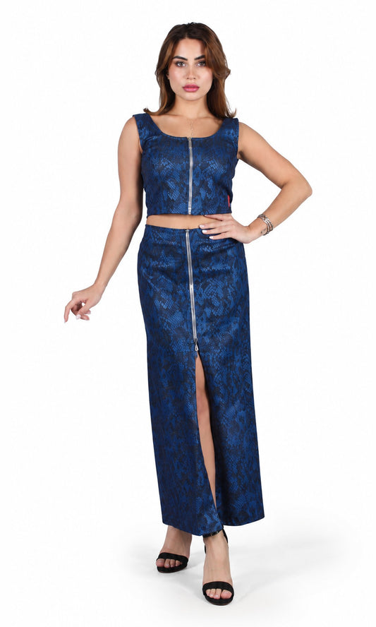 A woman modeling a two-piece blue patterned set consisting of a sleeveless crop top with a front zipper and a matching high-slit maxi skirt, photographed against a plain white studio background.