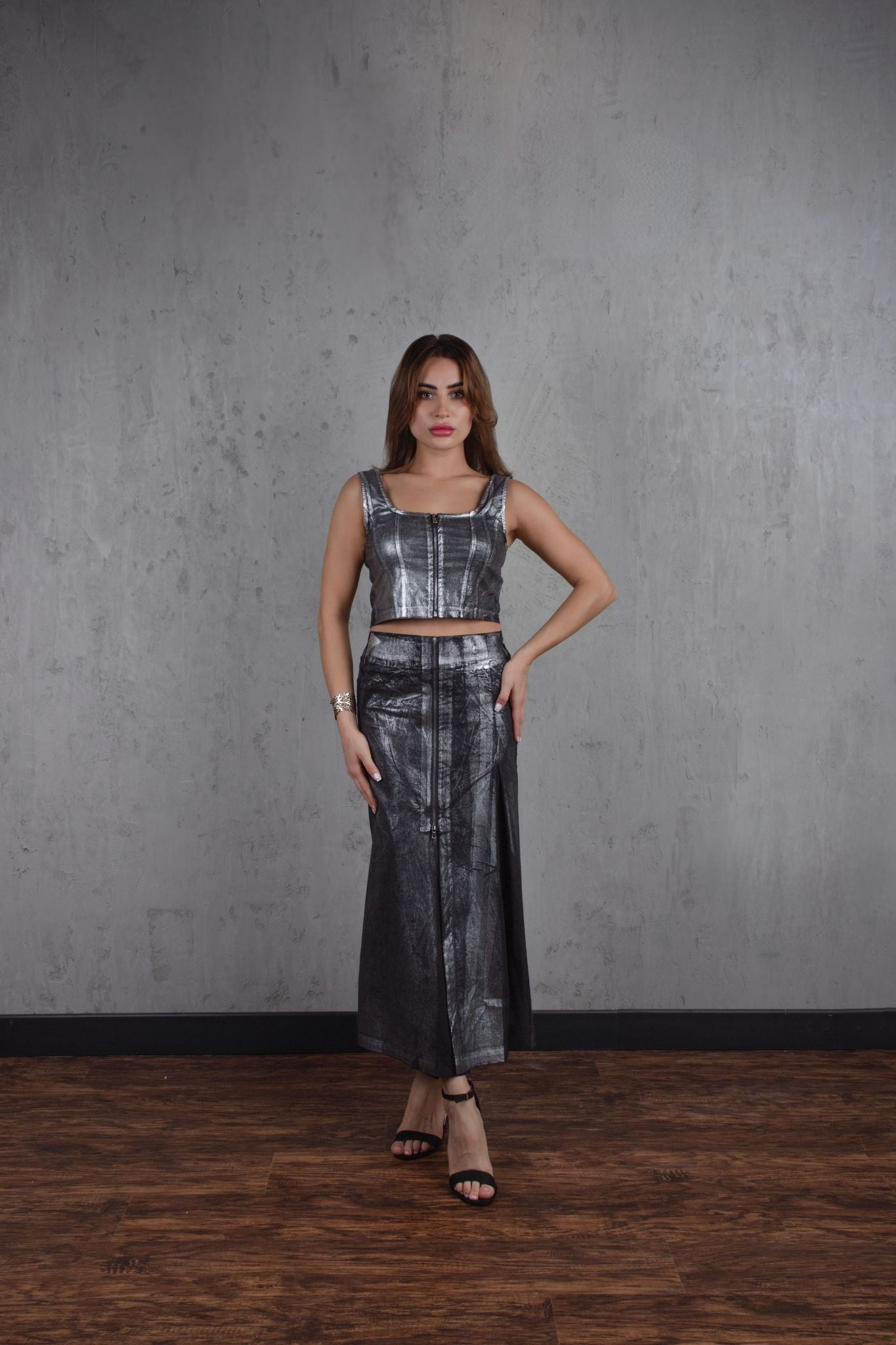 Woman wearing a metallic silver outfit against a gray wall.