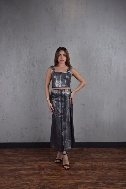 Woman wearing a metallic silver outfit against a gray wall.