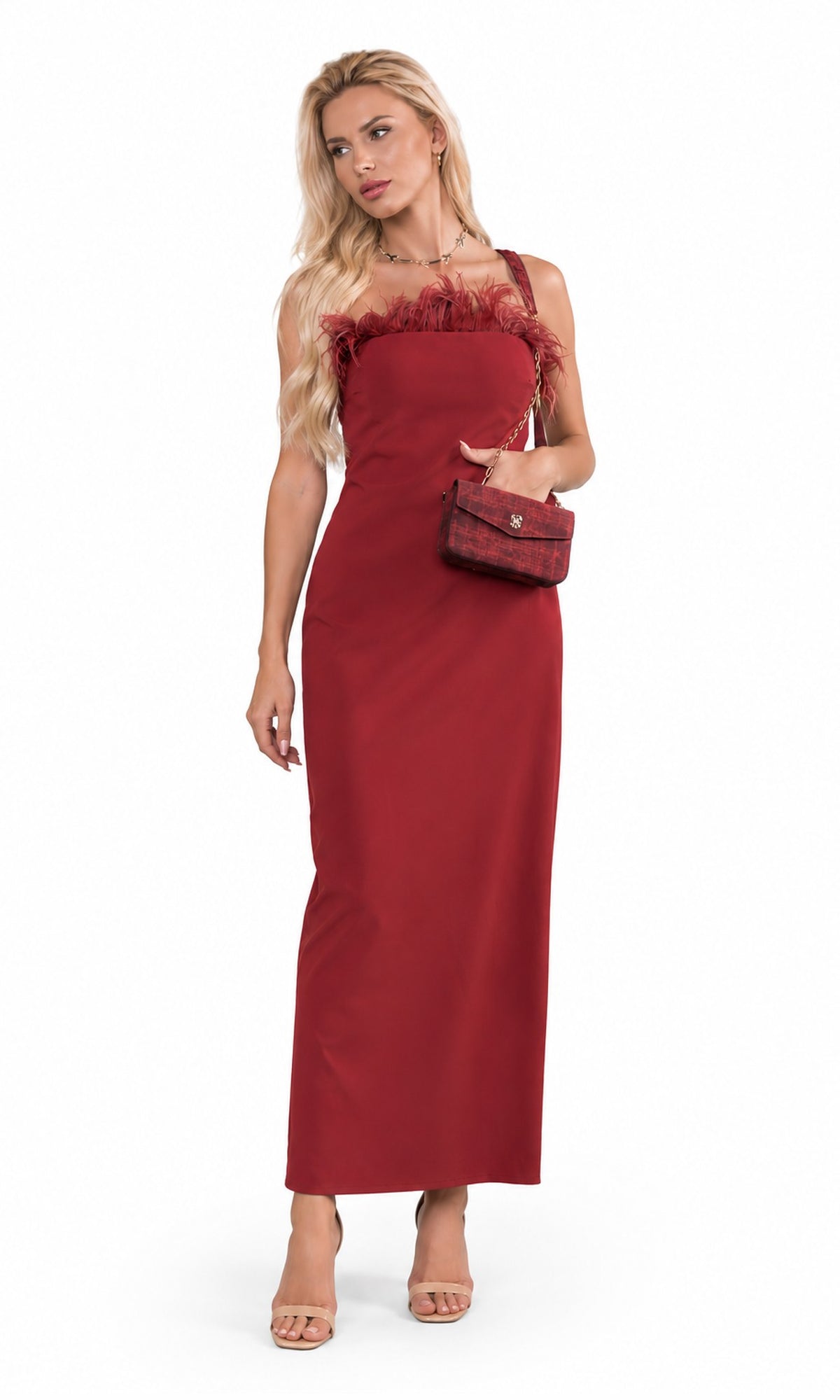 A blonde model wearing a sleeveless, floor-length red dress with ruffled trim at the neckline and holding a small red handbag, photographed against a plain white studio background.