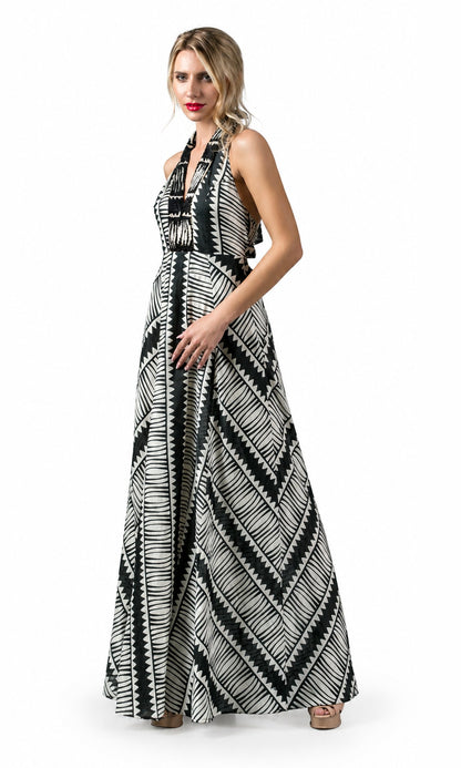 A woman modeling a sleeveless halter-neck maxi dress with a bold black and white geometric tribal pattern, set against a plain white studio background.