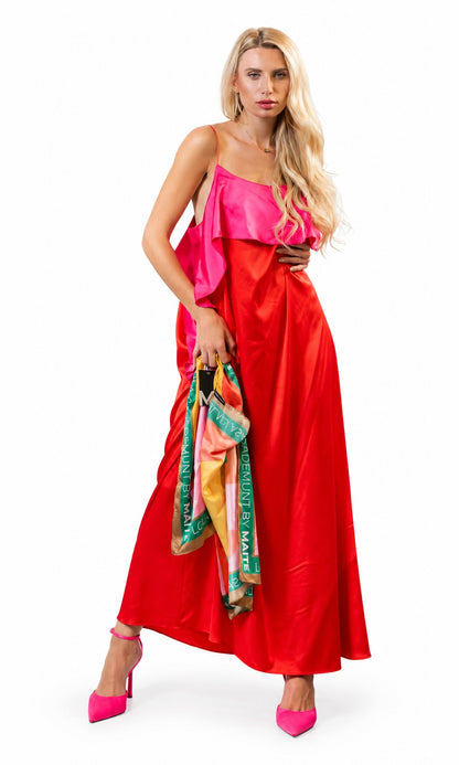 A blonde model wearing a vibrant red satin maxi dress with a bright pink ruffled neckline, holding a colorful patterned scarf, and wearing hot pink high heels against a solid white background.