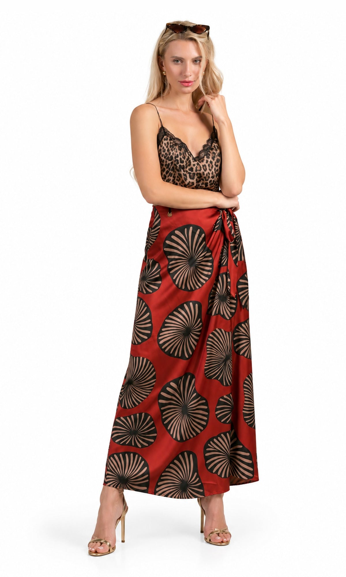 A woman modeling a two-piece outfit consisting of a leopard-print camisole top and a red maxi skirt with a black and beige sunburst pattern, set against a plain white background.
